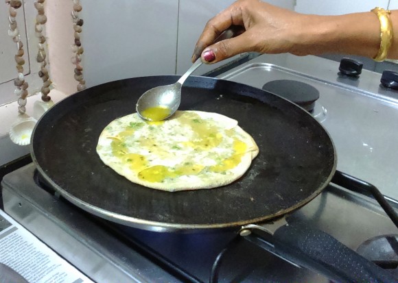 pouring ghee on the paratha