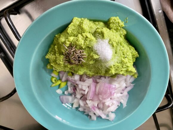 Take a mixing bowl; Put half quantity of ground green chana, chopped onion, salt