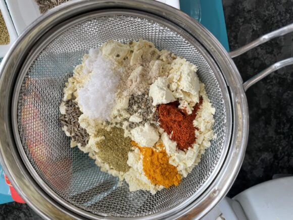 Sieve besan, salt, turmeric powder, chilli powder, asafoetida and coriander powder