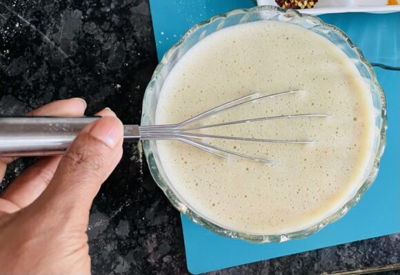 put sieved besan, curd, water, ginger paste, cumin, ajwain, Make a smooth paste