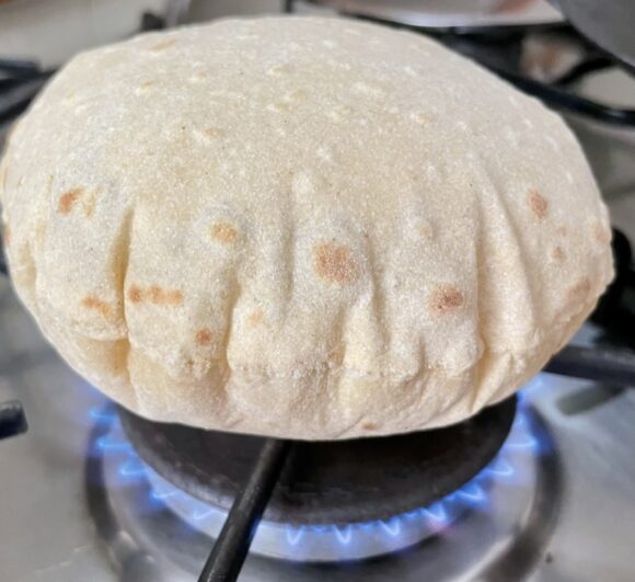 Now hold the chapati with tong and put directly on fire, first side on flame