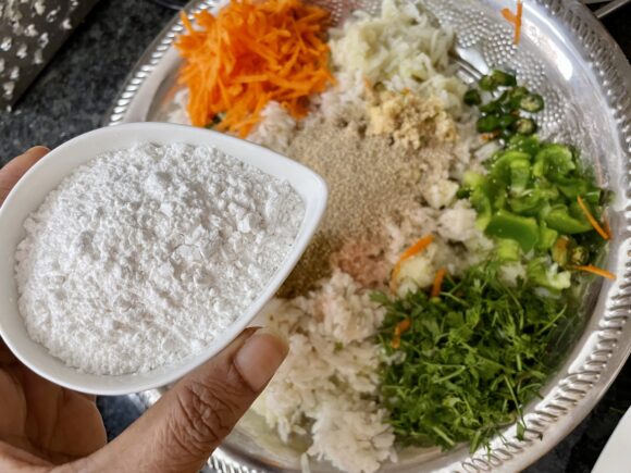 put soaked poha, chopped coriander, grated potato, carrot, chopped bell peppers, green chilli, ginger, fried onion, all powder masala, corn flour and salt.